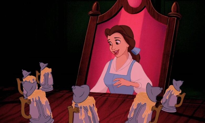 Belle looking into a mirror with mugs on a table in front of her.