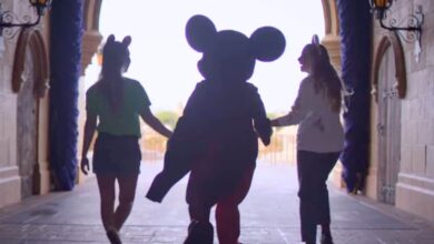 Mickey Mouse walks through Cinderella Castle at Disney World with two guests, capturing a magical moment in theme park history.