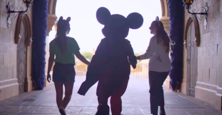 Mickey Mouse walks through Cinderella Castle at Disney World with two guests, capturing a magical moment in theme park history.