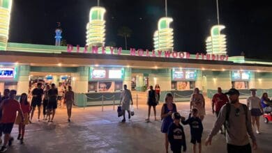 Guests heading toward the entrance of Disney’s Hollywood Studios at night.