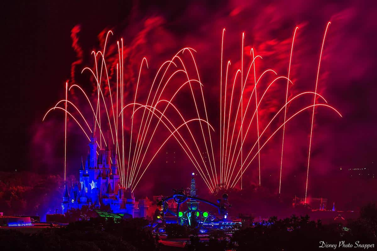 Red fireworks burst above Disney World’s glowing castle and attractions, capping off an epic finale for a magical park adventure.