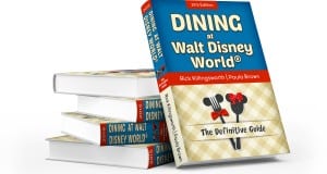 Stack of "Dining at Walt Disney World: The Definitive Guide" books with blue and beige covers, perfect for devoted Disney fans.