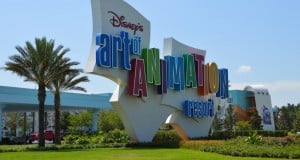 Vibrant Disney's Art of Animation Resort sign, palm trees and cars behind, highlighting a fun value stay at Walt Disney World.