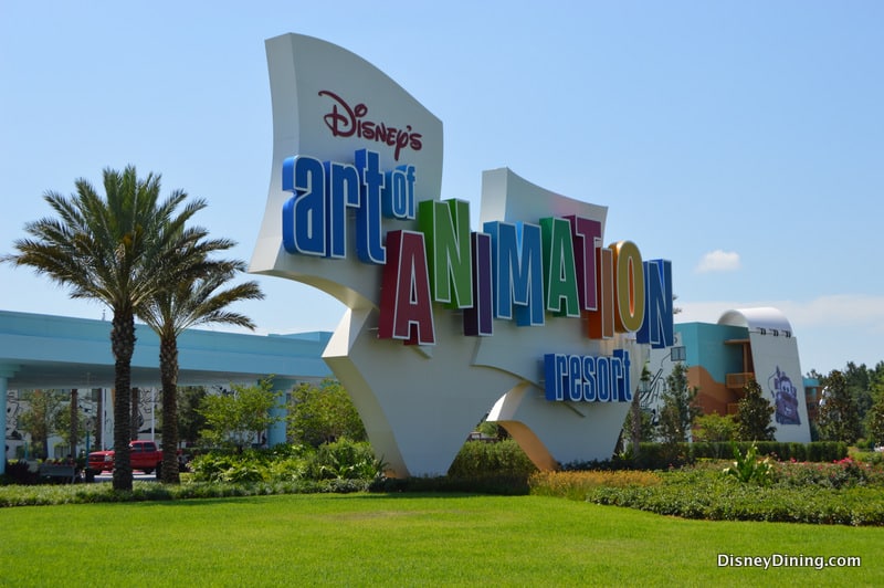 Vibrant Disney's Art of Animation Resort sign, palm trees and cars behind, highlighting a fun value stay at Walt Disney World.