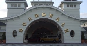Disney’s BoardWalk entrance with signature gold arch, parked cars, and bright flowers—steps from all the excitement near EPCOT.