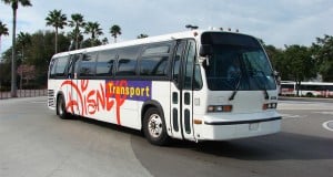 A Walt Disney World bus cruises by palm trees under blue skies, inviting guests to follow bus etiquette for magical park adventures.
