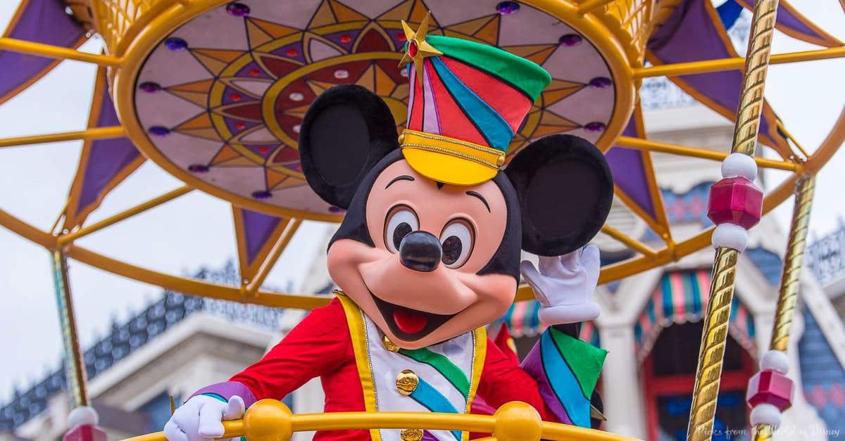 Mickey Mouse greets fans, waving in a dazzling parade uniform from a vibrant, gold-trimmed float at Walt Disney World.