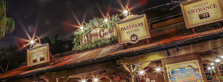 Jungle Cruise entrance at Disney World sparkling with holiday décor and FastPass+ signs, bustling with festive crowds at night.
