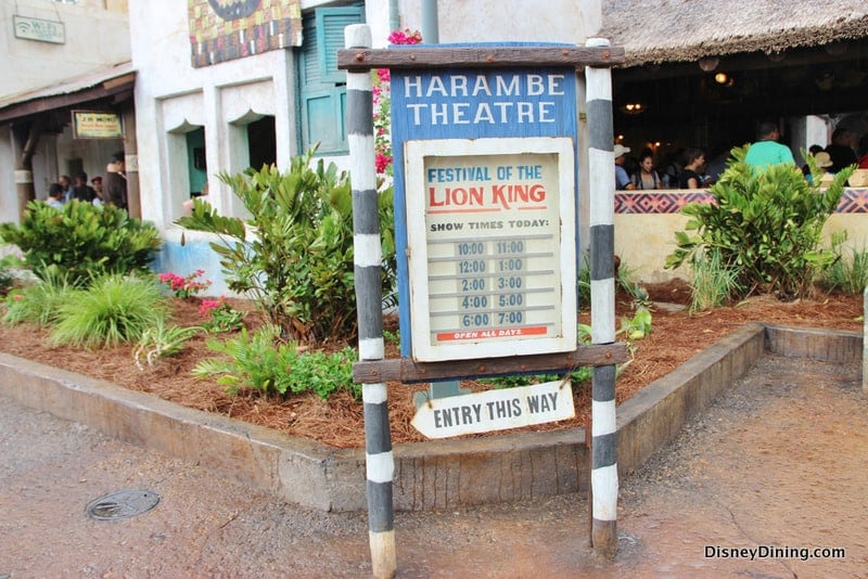 Harambe Theatre sign at Disney's Animal Kingdom shows "Festival of The Lion King" showtimes and an "Entry This Way" arrow.
