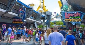 Guests explore Tomorrowland at Disney World, passing Stitch's Great Escape and Monsters, Inc. Laugh Floor attractions.