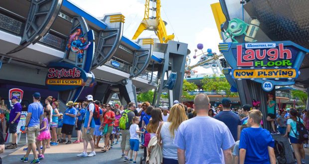 Guests explore Tomorrowland at Disney World, passing Stitch's Great Escape and Monsters, Inc. Laugh Floor attractions.