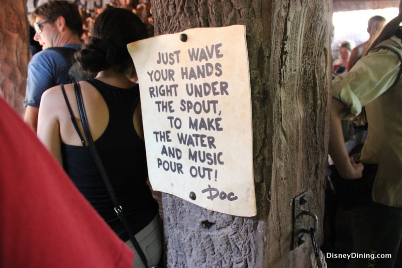 At Walt Disney World's interactive queue, a sign reads: "Wave your hands under the spout for water and music! – Doc.