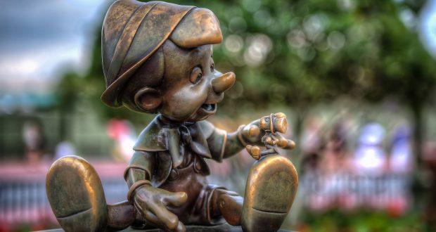 Pinocchio bronze statue holding Jiminy Cricket at Magic Kingdom, with a dreamy park backdrop—an iconic Disney photo spot.