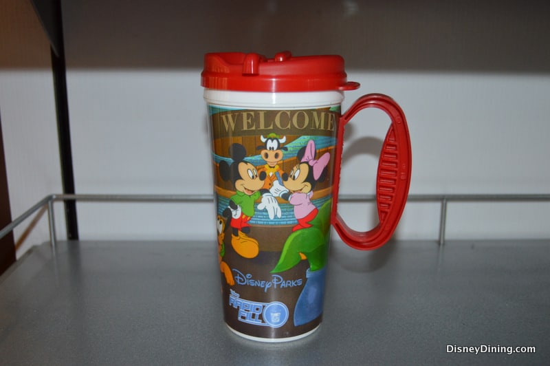 Disney Parks souvenir mug with red lid and handle, showcasing Mickey, Minnie, Goofy, and Pluto—ideal for Disney Parks fans.