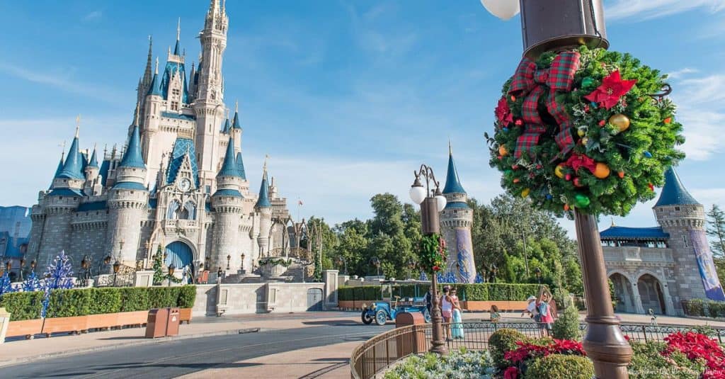 Cinderella Castle glows with Christmas decor and a bright sky—arrive early for festive, crowd-free Disney World holiday photos.