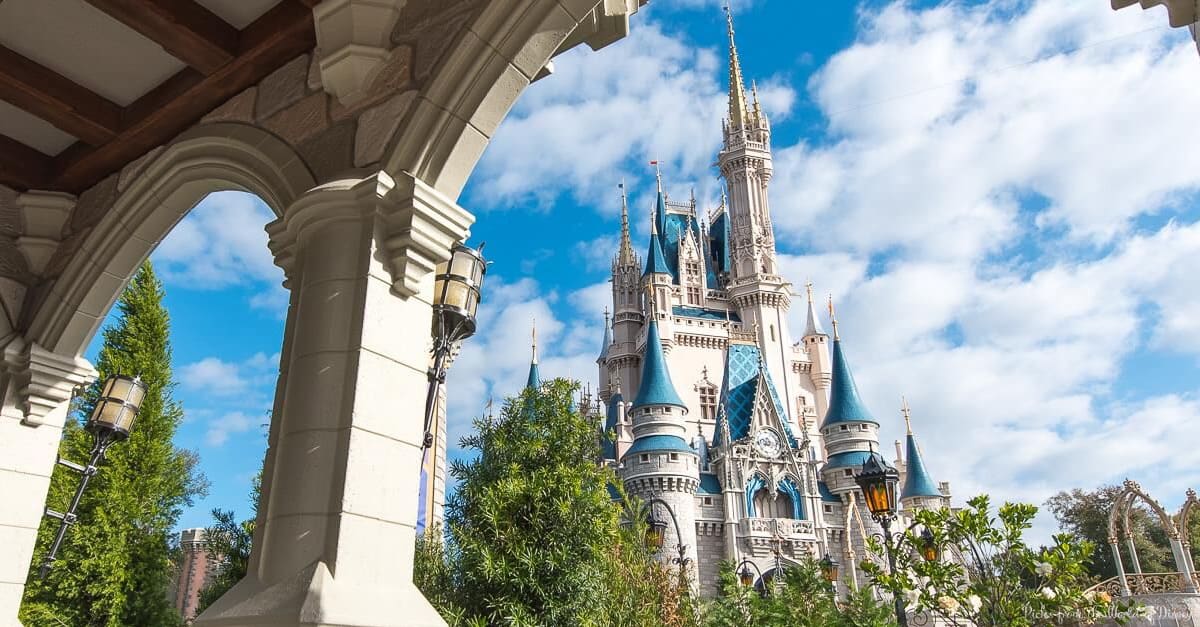 Cinderella Castle at Disney World, seen through an archway under blue skies, hints at magical park secrets to explore.