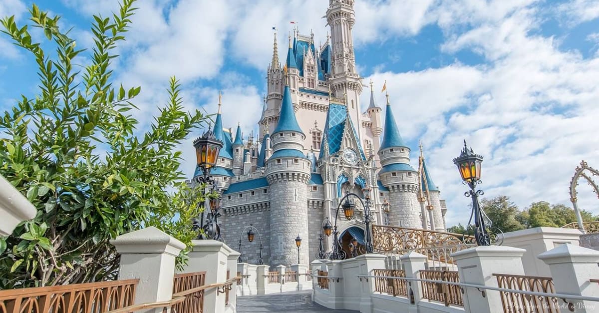 Cinderella Castle at Walt Disney World gleams with blue spires and lanterns, inviting guests along a sunny, magical Main Street.