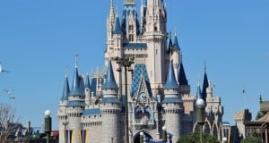 Cinderella Castle soars above excited Disney World guests, all eagerly gathering beneath the clear blue sky for magical experiences.