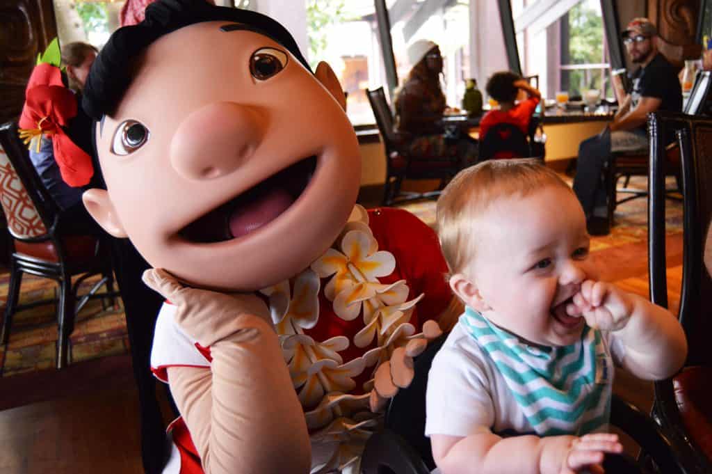 A happy baby sits next to Lilo at a Disney World restaurant, both smiling—Disney magic perfect for toddler-friendly fun.