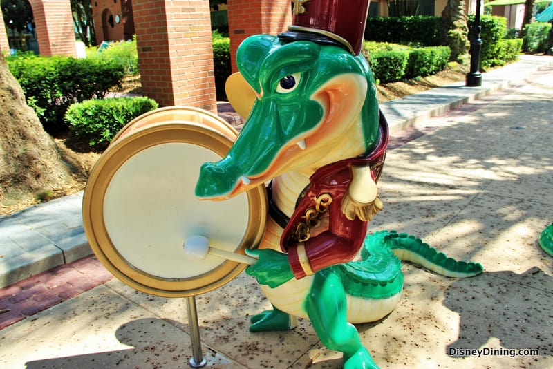 Louis the alligator from The Princess and the Frog drums in his vibrant marching band uniform at Disney’s Port Orleans–French Quarter.