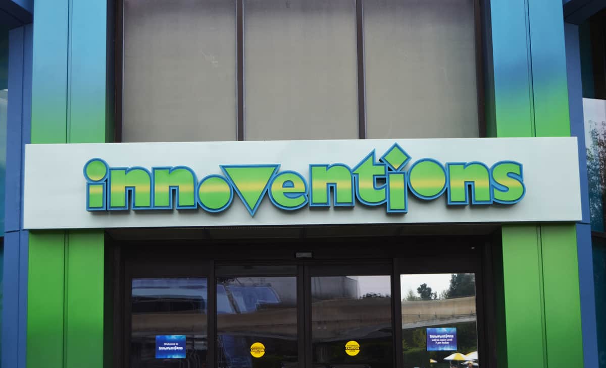 The colorful "Innoventions" sign welcomes guests above glass doors at Epcot’s vibrant, blue-and-green D-Zone entrance.
