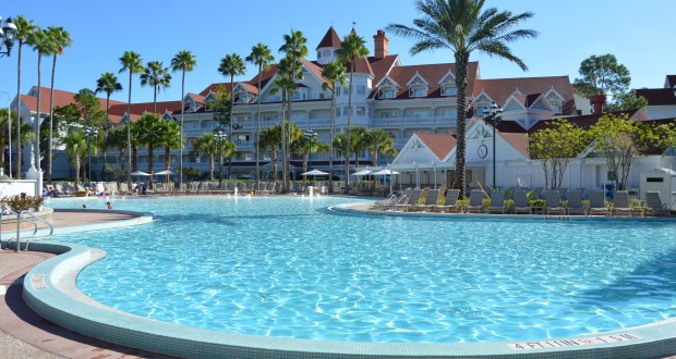 Disney World resort pool with sparkling blue water, palm trees, loungers, and the iconic hotel—an oasis for park guests.