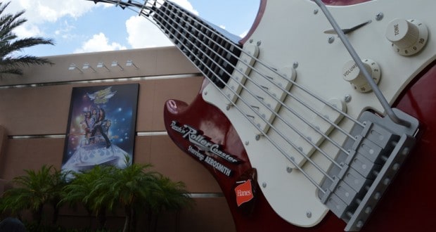 The iconic giant red and white guitar outside Rock 'n' Roller Coaster at Hollywood Studios, framed by palm trees and a mural.