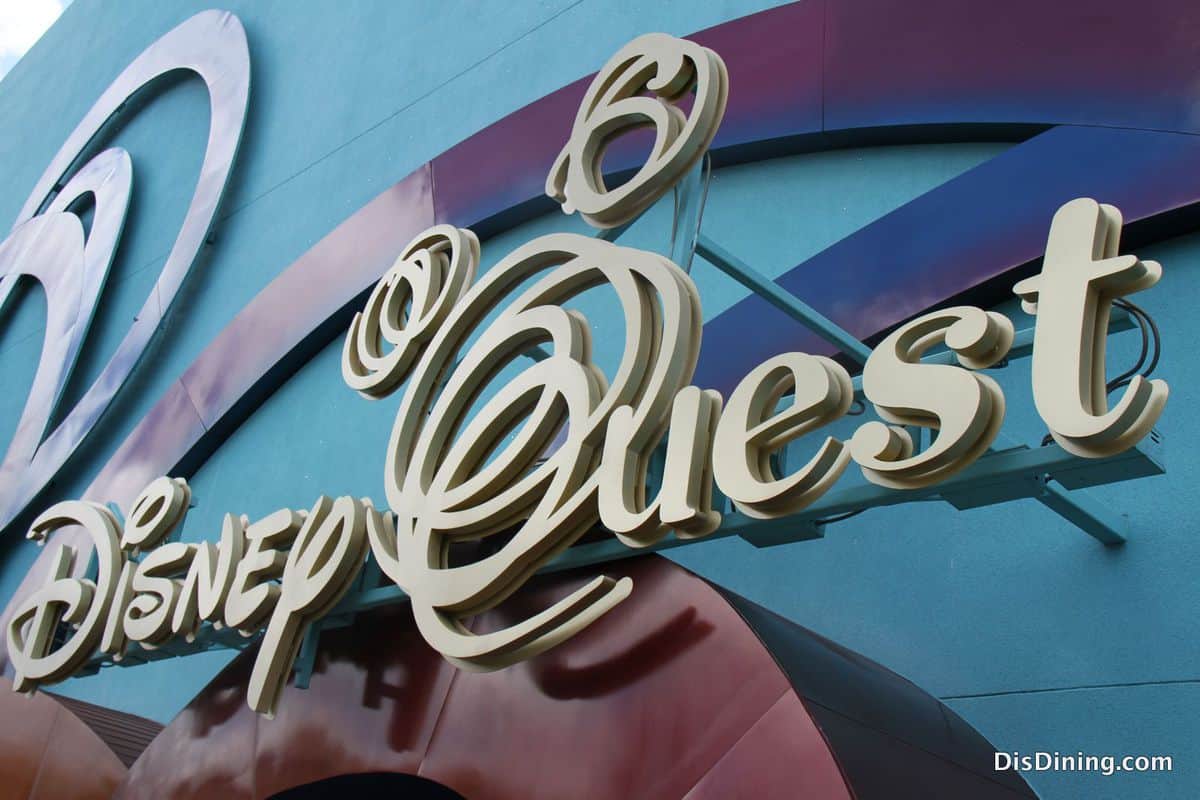 Disney Quest marquee against a blue wall and energetic abstract shapes, evoking the lively spirit of Downtown Disney pre-closure.