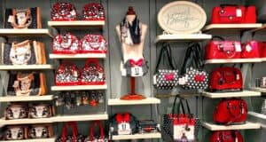 Minnie Mouse-inspired purses, bags, and wallets in classic red, black, and polka dot styles line the display shelves at Disney World.