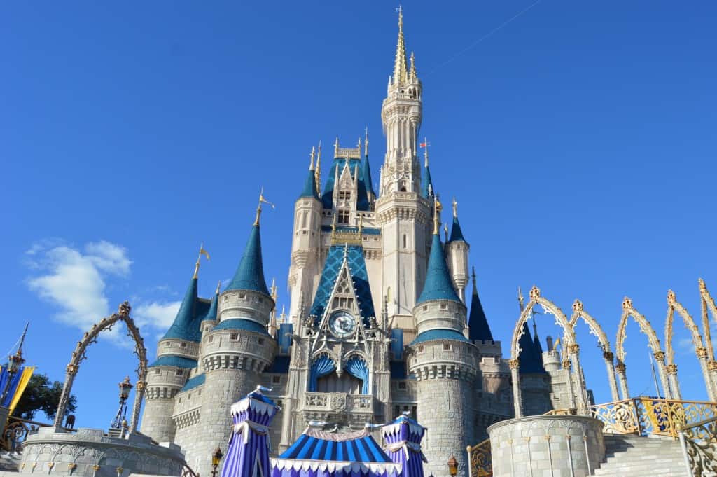 Cinderella Castle at Disney World dazzles with blue spires and gold trim beneath a sunny sky, a must-see for every fan.