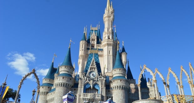 Cinderella Castle at Disney World dazzles with blue spires and gold trim beneath a sunny sky, a must-see for every fan.
