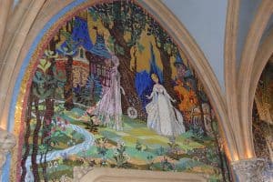 Disney-style mosaic featuring two women in pink and white dresses in an enchanted forest, cottage in back, evoking park magic.