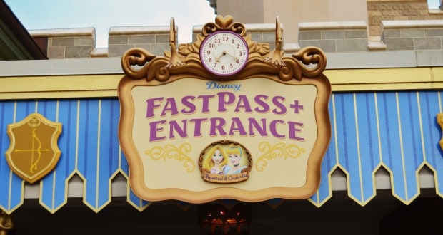 FastPass+ Entrance at Disney World, featuring a clock and princess images beneath a blue-and-yellow awning for easy access.