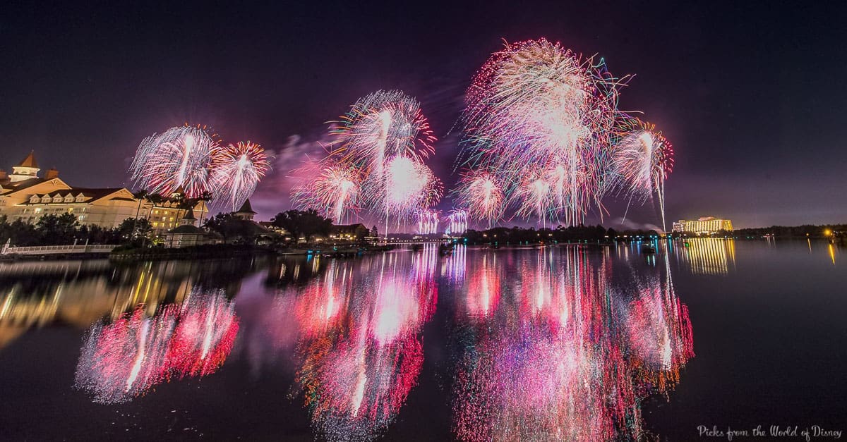 Dazzling fireworks burst over the water at Disney World, their vivid colors sparkling on the lake for an unforgettable spectacle.
