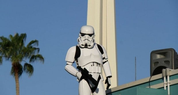 A stormtrooper stands atop a rooftop by a palm tree and tower at Disney's Hollywood Studios, possibly during attraction downtime.
