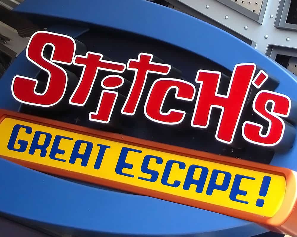 Stitch’s Great Escape! sign at Magic Kingdom, bold red and yellow on blue, marking the now-retired Tomorrowland attraction.