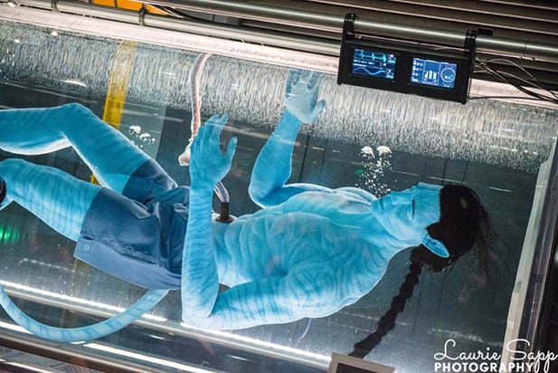An Avatar floats in a futuristic water tank with high-tech monitors above, evoking Pandora – The World of Avatar at Animal Kingdom.