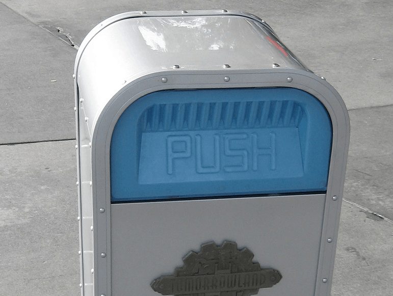 Classic Disney World PUSH trash can in light gray and blue, on concrete—an iconic detail loved by theme park fans.