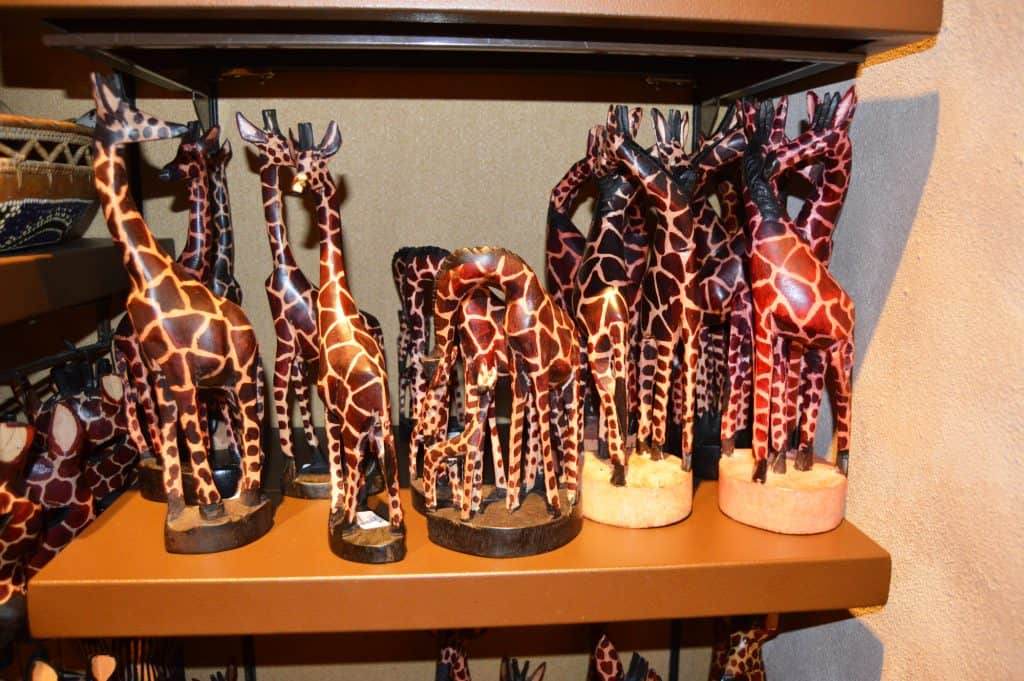 Hand-painted wooden giraffe figurines on display shelves, unique collectible souvenirs for Disney World fans hunting magical keepsakes.