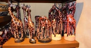 Hand-painted wooden giraffe figurines on display shelves, unique collectible souvenirs for Disney World fans hunting magical keepsakes.
