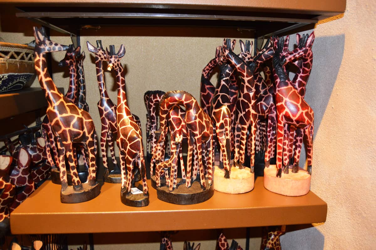 Hand-painted wooden giraffe figurines on display shelves, unique collectible souvenirs for Disney World fans hunting magical keepsakes.