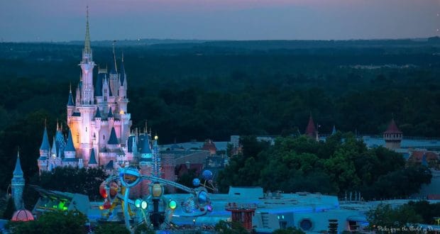 Cinderella Castle and Tomorrowland attractions glow among trees at sunset in Magic Kingdom—a top pick for thrill-seekers.