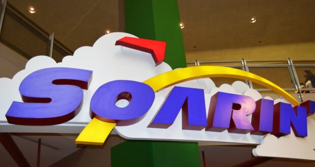 Vibrant "Soarin'" sign with clouds and a yellow arc greets Disney fans, signaling adventure at Walt Disney World's beloved attraction.