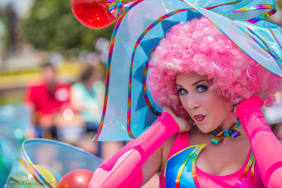 A lively entertainer in a pink wig and vibrant costume brings energy to a Walt Disney World event, capturing the park’s excitement.