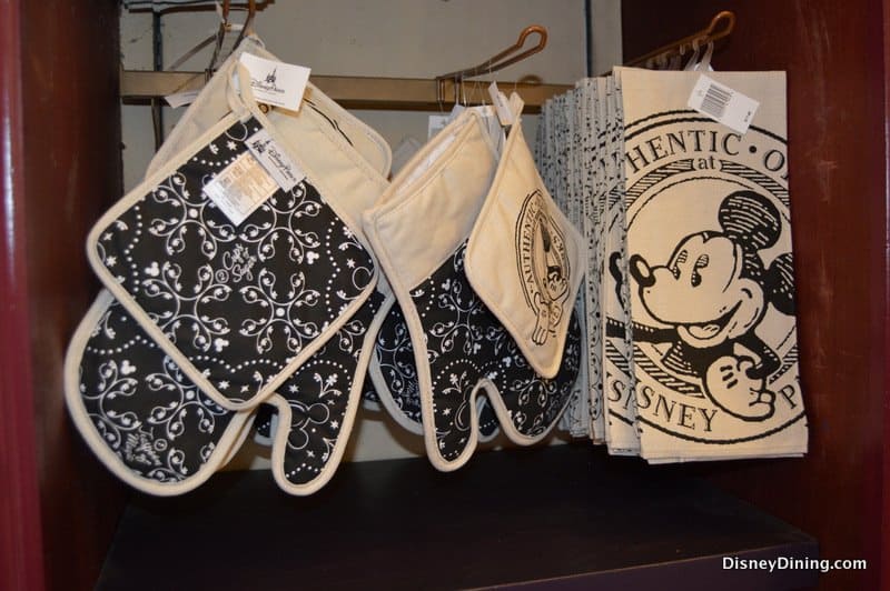 Black and white Mickey Mouse oven mitts and towels displayed in-store—must-have Disney Parks kitchen souvenirs for true fans.