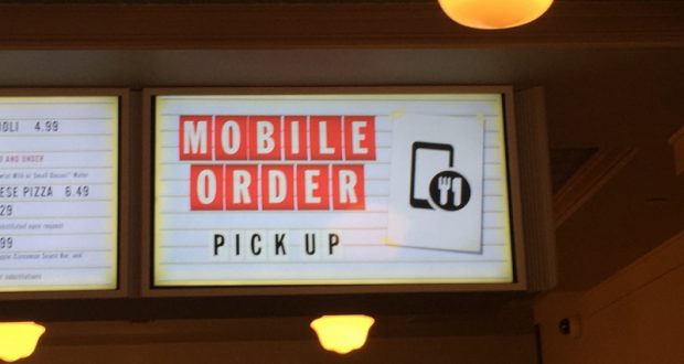 Mobile Order Pick Up" sign with smartphone and dining icons on a Disney World restaurant wall—perfect for skipping the lines!.