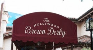 The Hollywood Brown Derby entrance at Disney's Hollywood Studios, marked by a burgundy awning with white script signage.
