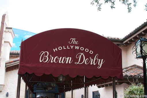 The Hollywood Brown Derby entrance at Disney's Hollywood Studios, marked by a burgundy awning with white script signage.