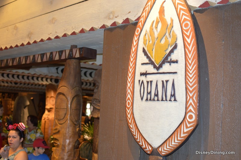 'Ohana restaurant sign glowing with a flame logo and lush tropical decor, bustling with guests at Walt Disney World.