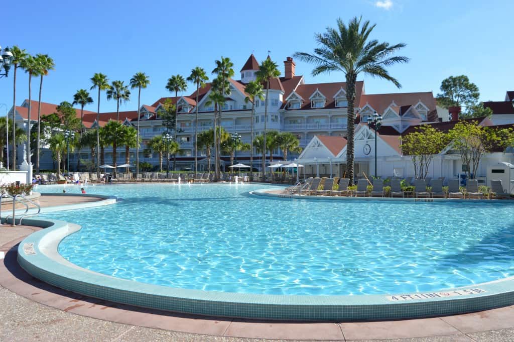 Inviting resort pool with sparkling blue water, palm trees, lounge chairs, and a hotel—just minutes from Walt Disney World magic.